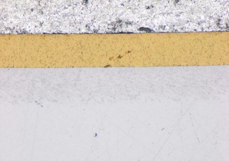 Lichtmikroskopischer Querschliff: goldfarbene TiN-Schicht auf Grundwerkstoff