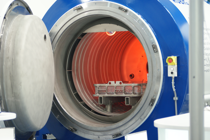 Gasnitrieranlage RÜBIG mit geöffneter Kammer – glühender Innenraum und Werkstückträger für Wärmebehandlung