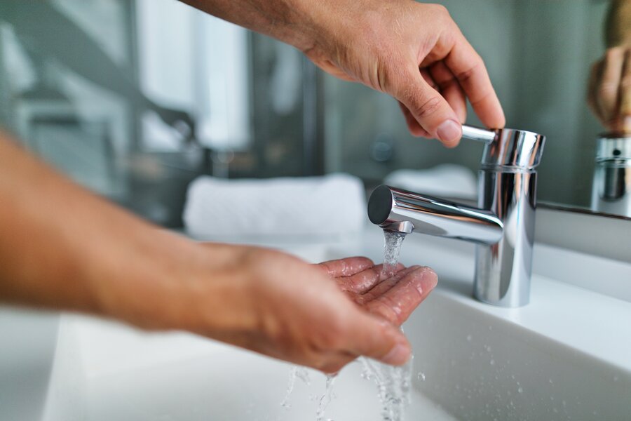 Hände die einen Wasserhahn bedienen und sich die Hände waschen