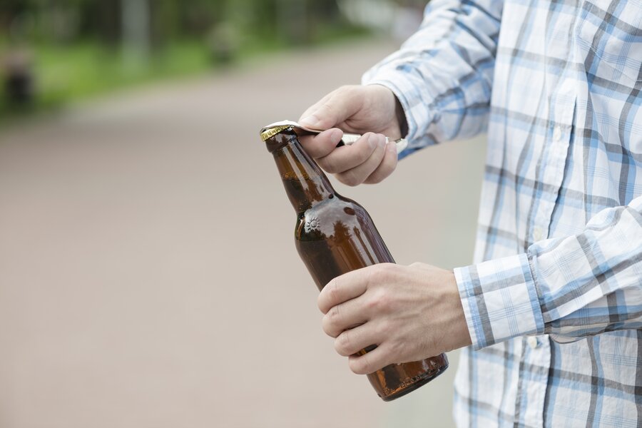 ein Mann der ein Bier mit einem Flaschenöffner öffnet