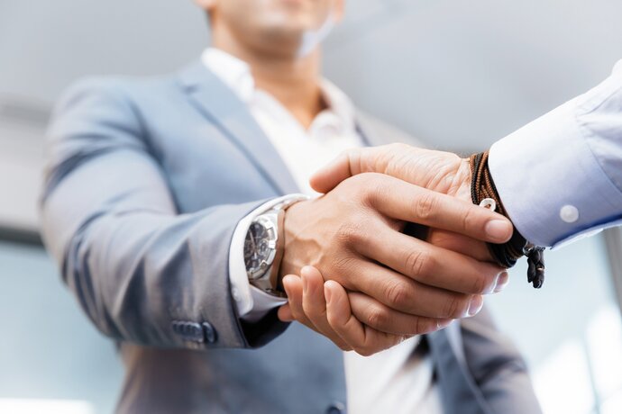 zwei Geschäftsmänner die sich die Hände schütteln, einer trägt dabei eine Uhr