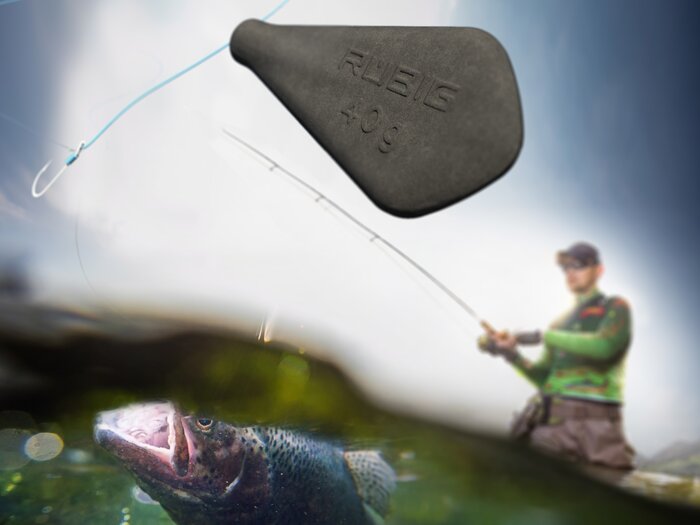 RÜBIG Angelgewicht mit 40 g im Fokus, im Hintergrund ein Angler beim Drill und eine Forelle unter Wasser – nachhaltige Alternative zu Bleigewichten