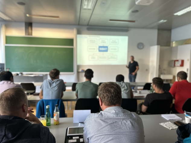 Teilnehmer der RÜBIG Seminare: Werkstofftechnik und Wärmebehandlung verfolgen eine Präsentation in einem modernen Schulungsraum.