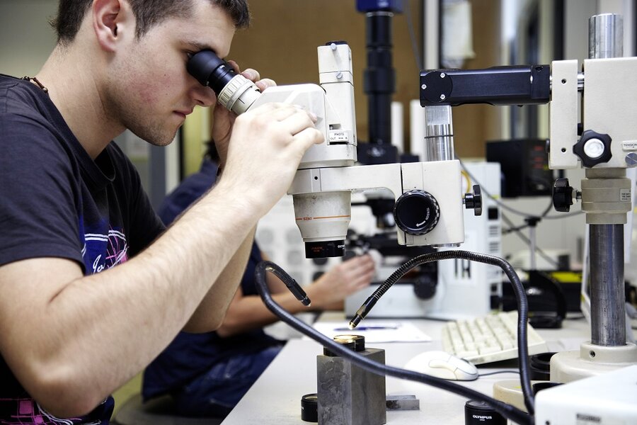 Ein RÜBIG Mitarbeiter vor einem Mikroskop beim Untersuchen von Bauteilen 